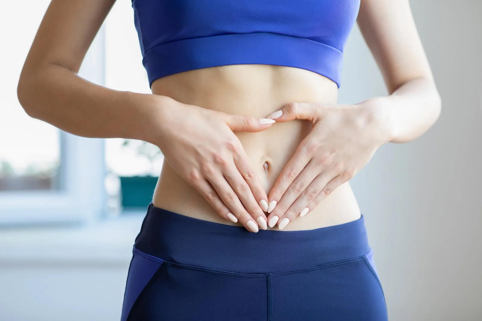 Una mujer apoya ambas manos sobre el abdomen