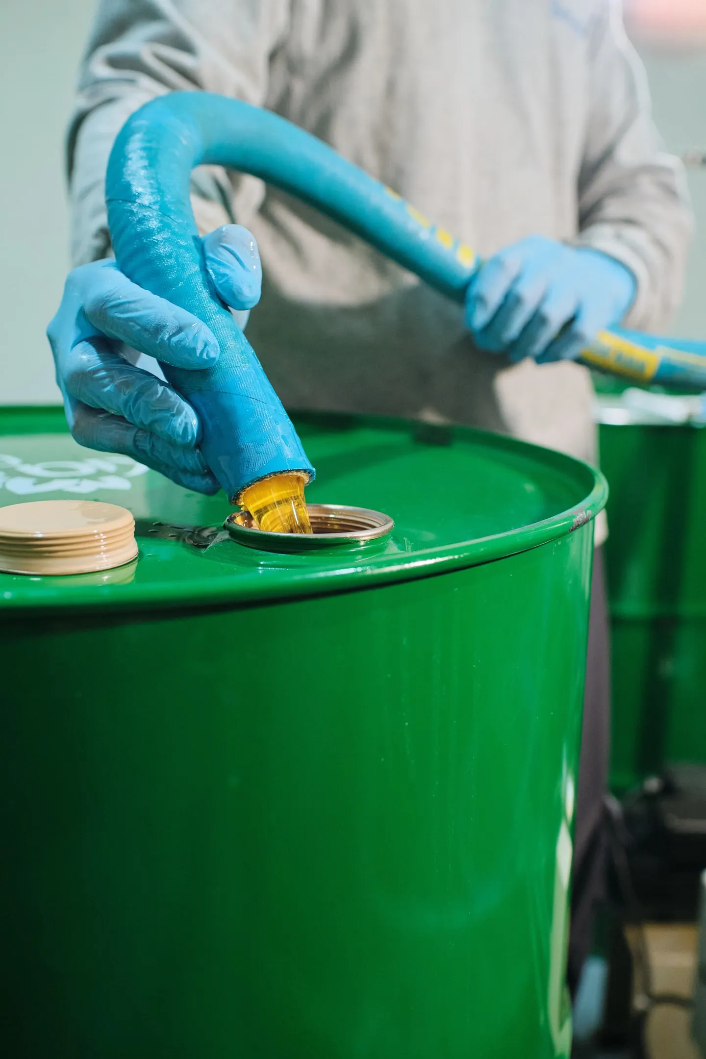 Gloved hands filling a drum with chia oil