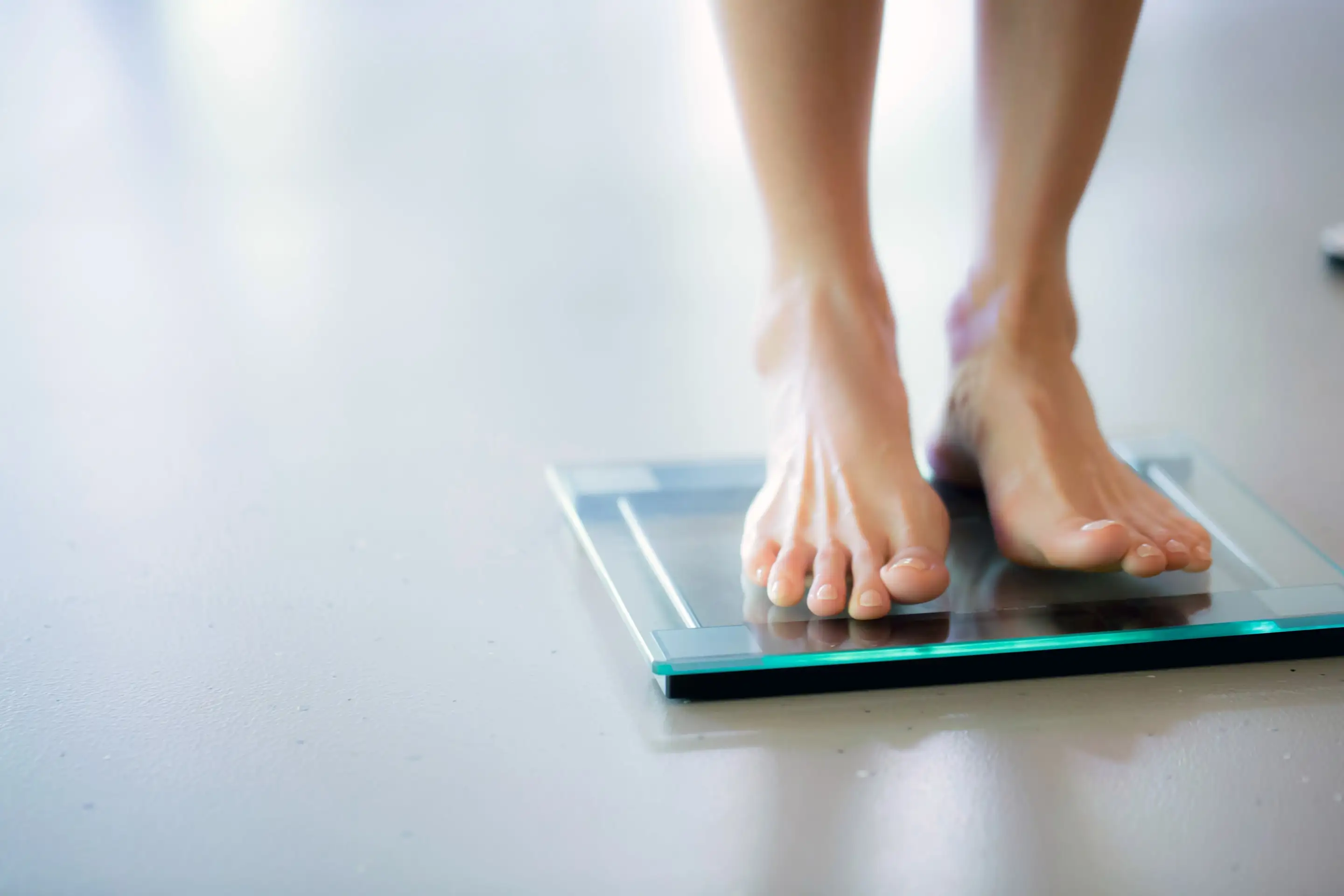 Los pies de una persona sobre una balanza de vidrio