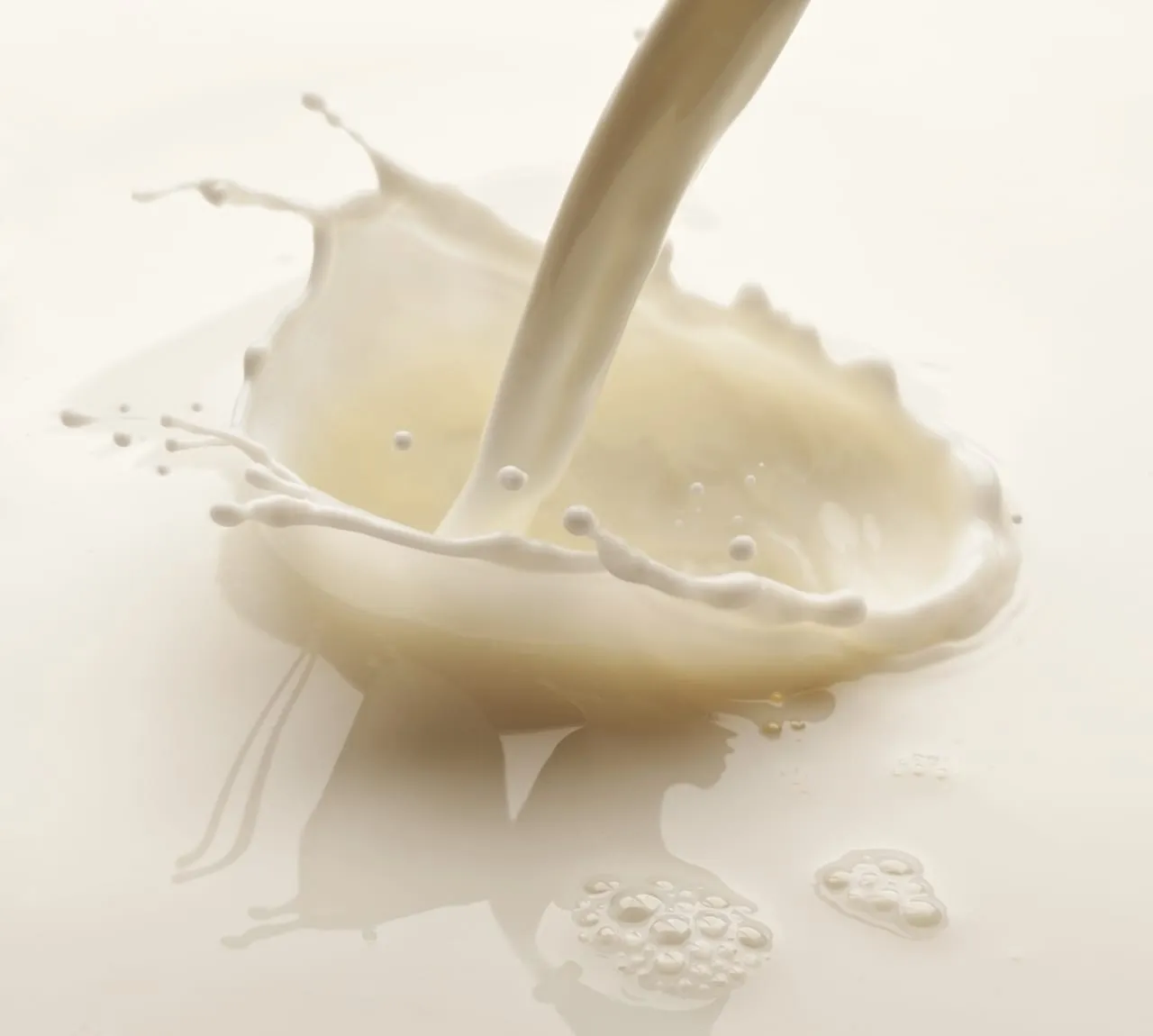 Plant-based milk poured into a splash on a pale surface